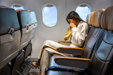 Asian woman is vomitting in the airplane during the flight using vomit bag due to the motion and...