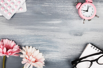 women health concept. copy space. pills, flower, notebook and clock on blue wooden background. wellness, medicine, personal and physical health.