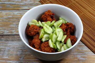 Pile of traditional spicy Thai fishcake topping with fresh cucumber serving in the bowl. Famous appetizer menu in Asia restaurant.