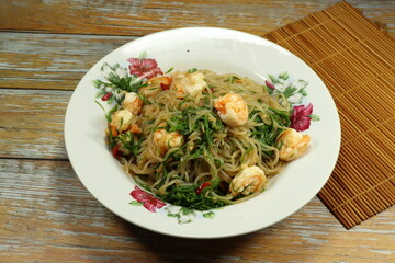 Traditional spicy fried noodle with fresh peel shrimp and climbing wattle serving on the plate. Famous street food menu in Asia.