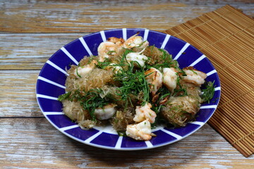 Traditional spicy fried noodle with fresh peel shrimp and climbing wattle serving on the plate. Famous street food menu in Asia.