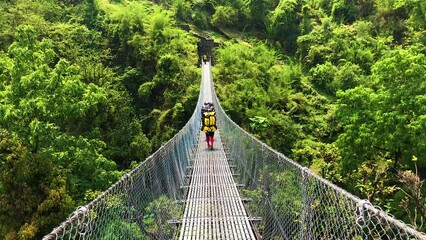 Porter carry a heavy load on his back over the suspension bridge in Annapurna region, Nepal