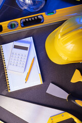 Contractor theme. Plans,  notebook and tool kit of the contractor: yellow hardhat, libella, saw and...