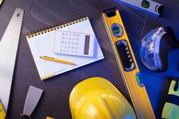 Contractor theme. Plans,  notebook and tool kit of the contractor: yellow hardhat, libella, saw and...