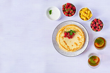 Pancakes with caramelized apples, raspberries, strawberries and red currants. Brunch with green tea and crepes.