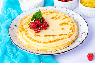 Pancakes with caramelized apples, raspberries, strawberries and red currants. Brunch with green tea and crepes.