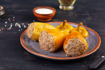Colorful stuffed peppers with rice and minced meat on wooden background.