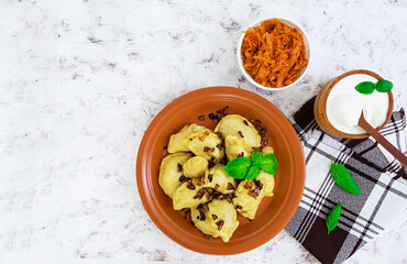 Delicious dumplings with cabbage and sour cream on white background. Top view