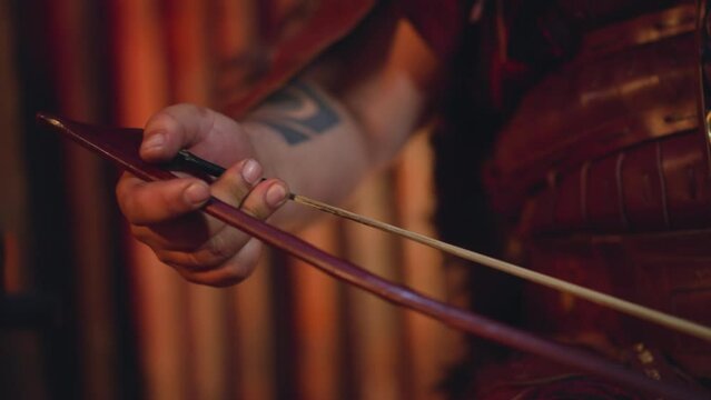 Man in leather clothes plays string instrument with bow at folk music concert on stage closeup. Altai musical instruments. Ancient culture and art