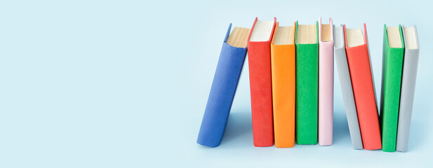 Stack of books on light blue background with space for text