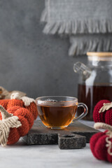  Mug with black tea with knitted decorative pumpkins. The concept of autumn and coziness. Autumn tea.