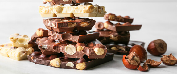 Pieces of tasty different chocolate with nuts on light table