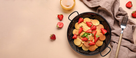 Composition with frying pan of mini pancakes and strawberry on beige background with space for text