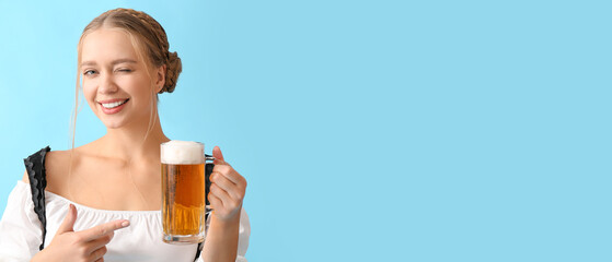Beautiful woman in traditional German costume and with mug of beer on blue background with space for text