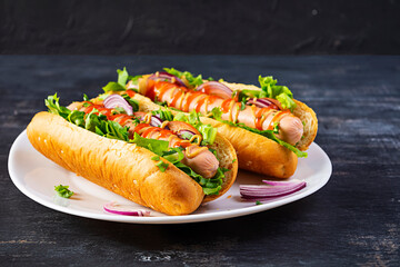 Homemade hot dog with sausage, salad, carrot, cucumber and tomato on wooden background