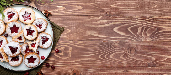 Plate with tasty Linzer cookies on wooden background with space for text