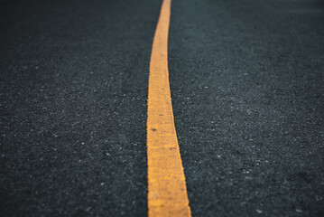 Black asphalt road surface texture with a yellow line.