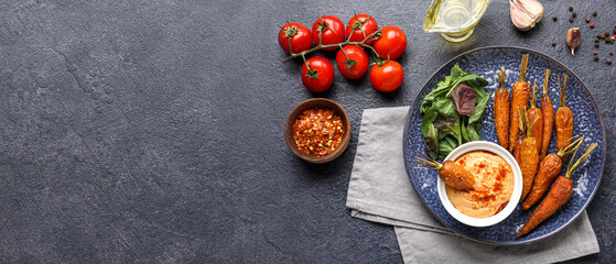Plate with tasty baked carrots and sauce on dark background with space for text