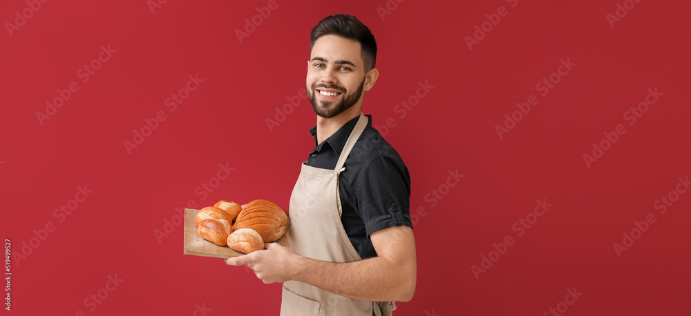 Wall mural baker with fresh bread on red background