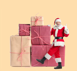 Happy Santa Claus with big gifts on beige background