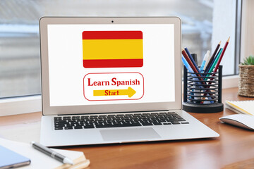 Modern laptop with text LEARN SPANISH on screen at workplace