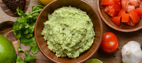 Tasty guacamole and ingredients on wooden background, top view