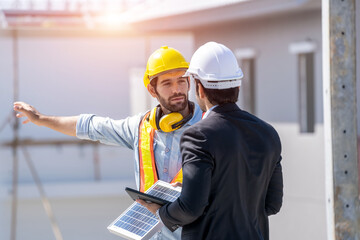 Engineers with Businessmen discussing and checking solar cell for residential under construction.