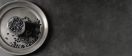 Jar with black beans on dark background with space for text