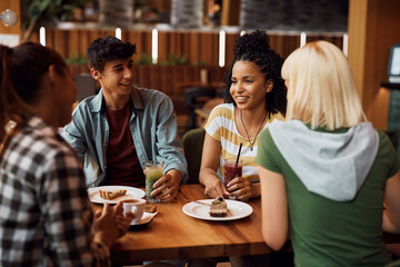 Happy African American woman and her friends enjoying in conversation in cafe.