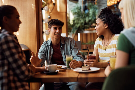 Multiracial Group Of Happy Friends Talking While Gathering In Cafe.