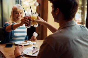 Close up of couple drinking juice and toasting in cafe.