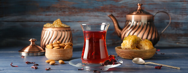Tasty Turkish tea in glass cup with sweets on table