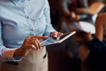 Close up of black waitress working on touchpad in restaurant.