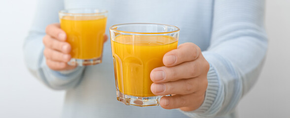 Woman with glasses of healthy turmeric drink on light background, closeup