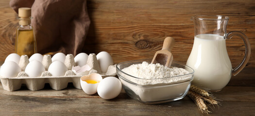 Wheat flour with eggs and milk on wooden background