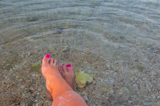 Women's legs, ankles, in a warm transparent sea. Pure clear water