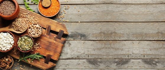 Different raw legumes on wooden background with space for text