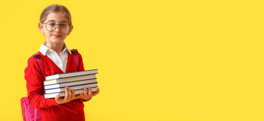 Cute little school girl holding books on yellow background with space for text