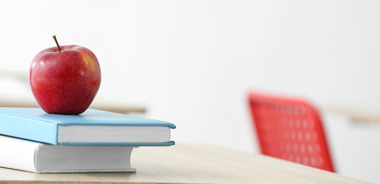 Apple and books on desk in classroom