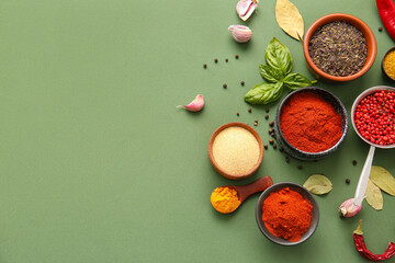 Composition with bowls of different spices on green background