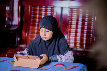 Islamic girl playing tablet at home
