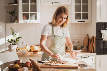 charming young woman in chef's apron preparing pie at home in the kitchen Cozy home interior