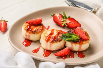 Plate with delicious cottage cheese pancakes covered with sauce and berries on white wooden table