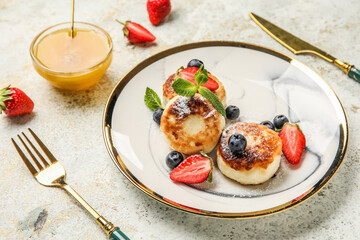 Plate with cottage cheese pancakes, delicious berries and mint leaves on light table