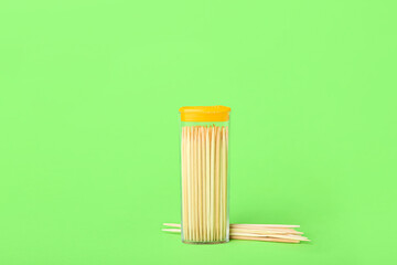 Holder with toothpicks on green background