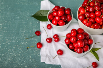 Composition with bowls of sweet cherries on color background