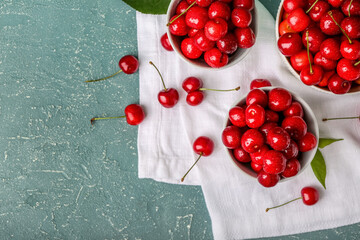 Composition with bowls of sweet cherries on color background