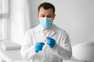 Fototapeta premium Male doctor with syringe in clinic