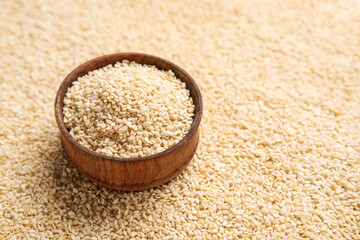 Wooden bowl with sesame seeds as background