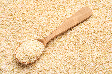 Wooden spoon with sesame seeds as background
